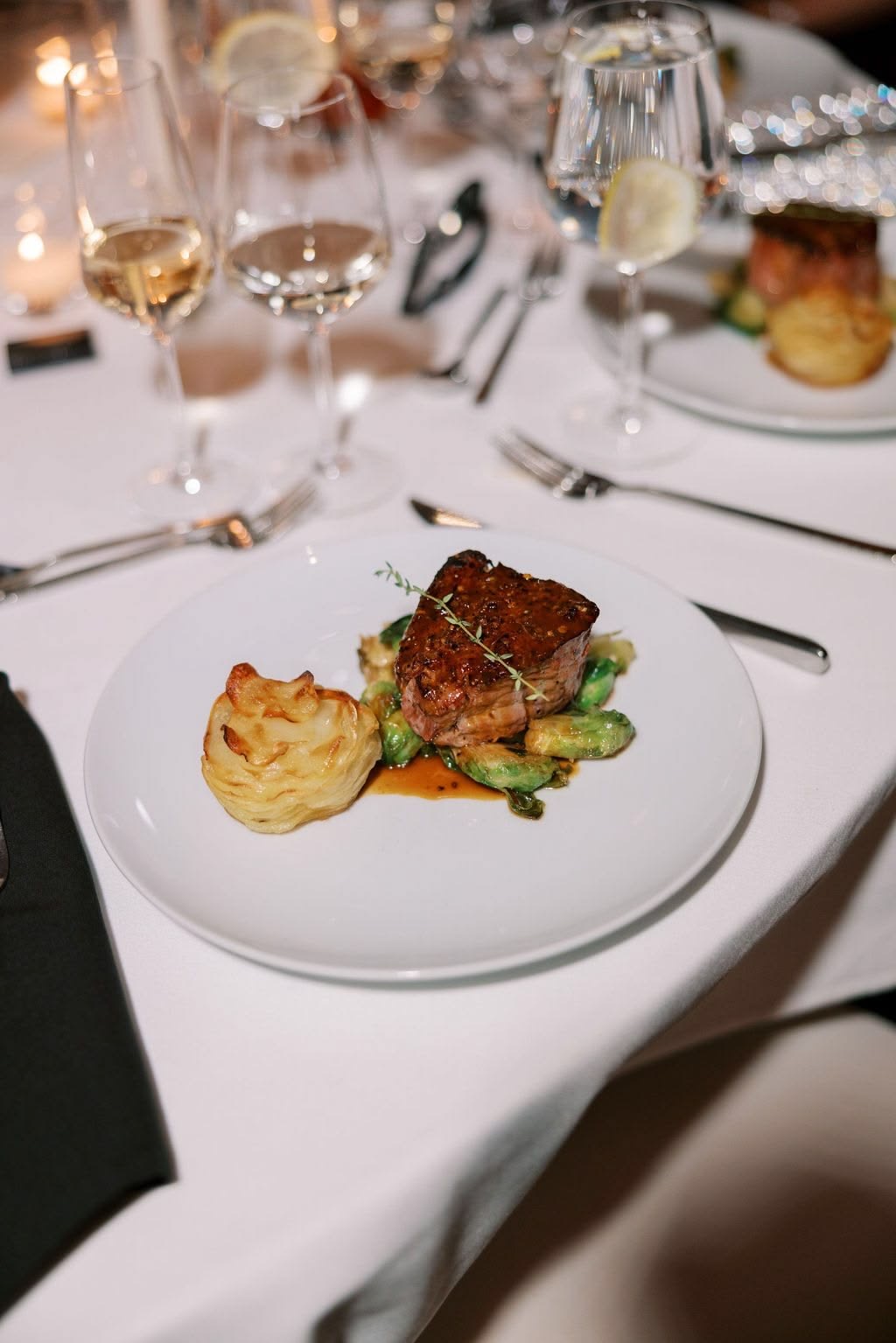 Fresh Chef wedding dinner: plated steak entrée with potato, vegetables and candlelit wine glasses