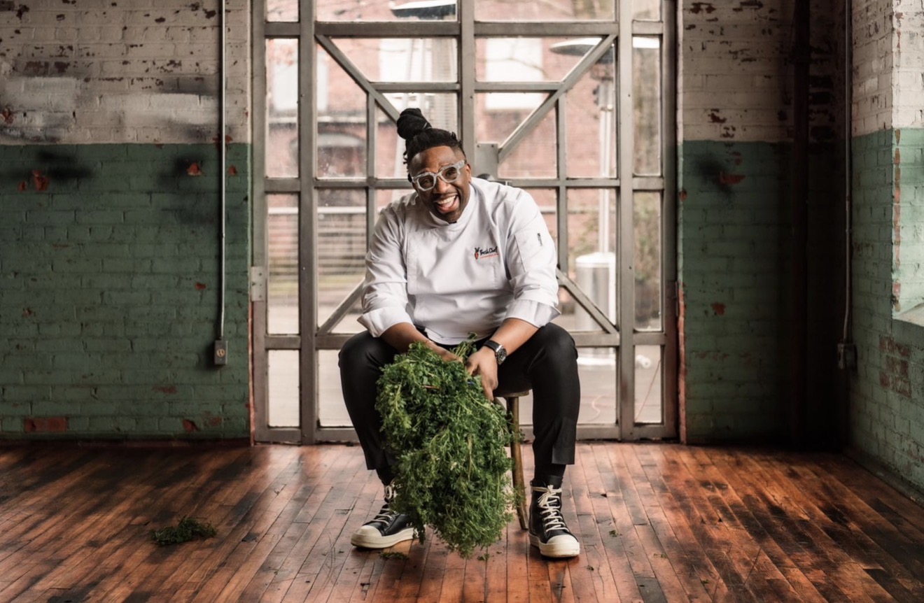 Chef Ameer, founder of Fresh Chef, seated in an industrial studio holding a bundle of fresh herbs